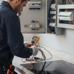 Électricien vérifiant les fils d'une plaque de cuisson moderne pour un branchement sécurisé.