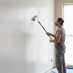 Un bricoleur utilisant un rouleau pour appliquer de l'enduit sur un mur intérieur.